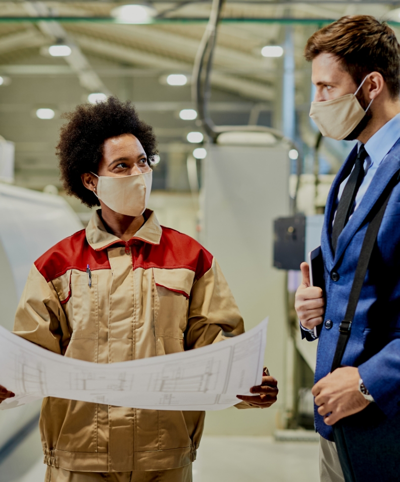 black-female-worker-explaining-design-plans-company-manager-who-is-visiting-factory-facility-coronavirus-pandemic